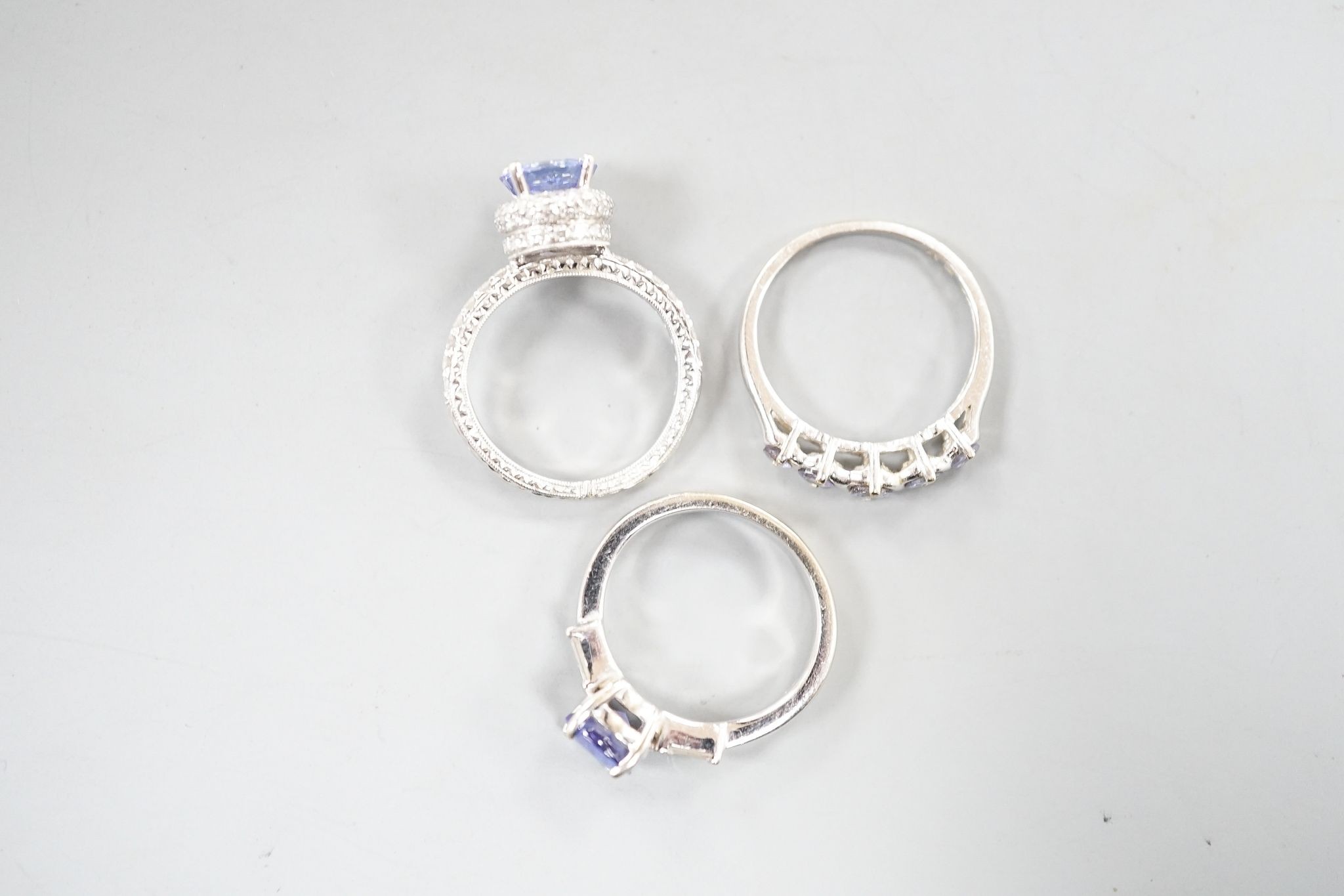 Two modern 18k white metal, tanzanite and diamond set dress rings, size J, gross 8.3 grams and a modern 9ct white gold and gem set ring, gross 2 grams.